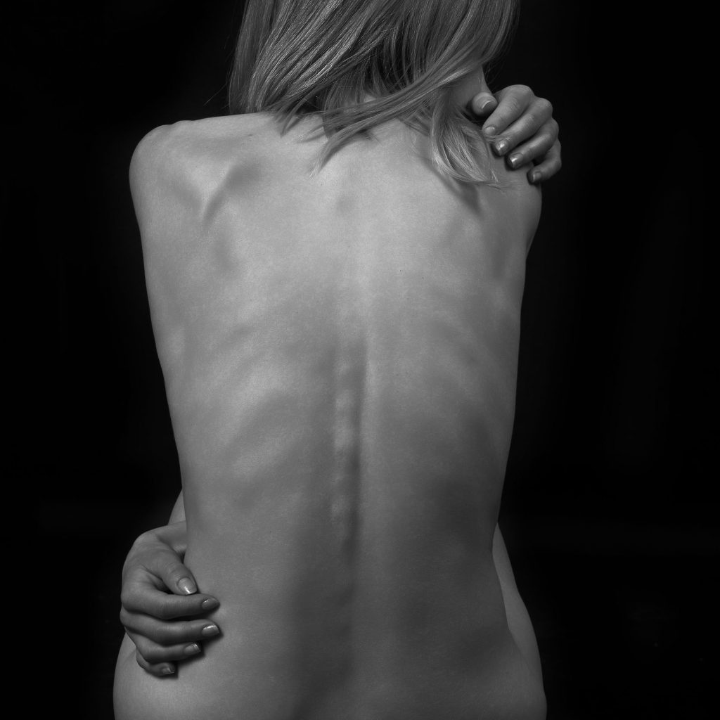 Fotografie alb-negru cu detaliu artistic al spatelui, accent pe liniile fine si forma feminina