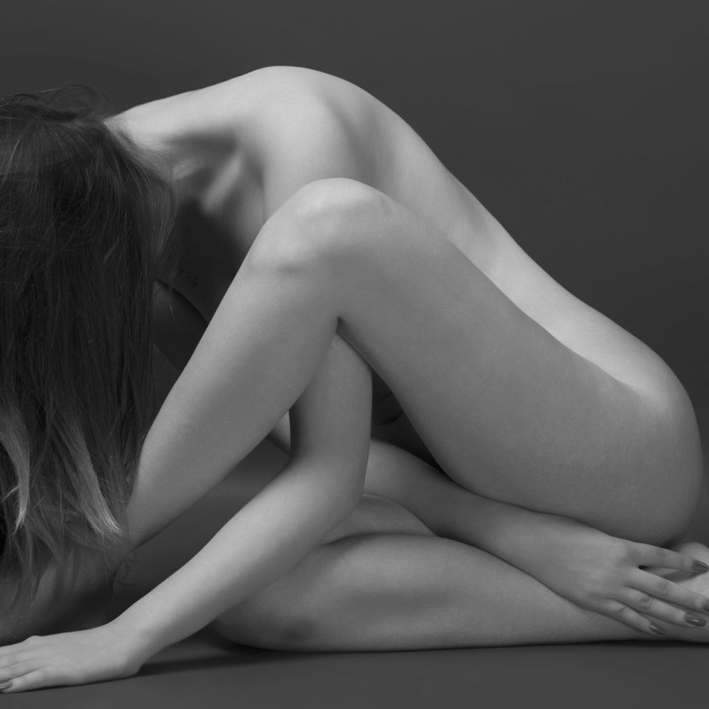 fotografie de studio fine art nude cu o femeie asezata pe podea intr-o postura feminina