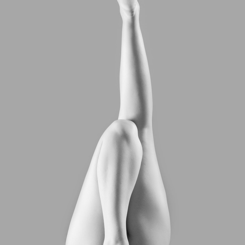 Fine art nude cu o femeie pe podea din spate avand un picior ridicat