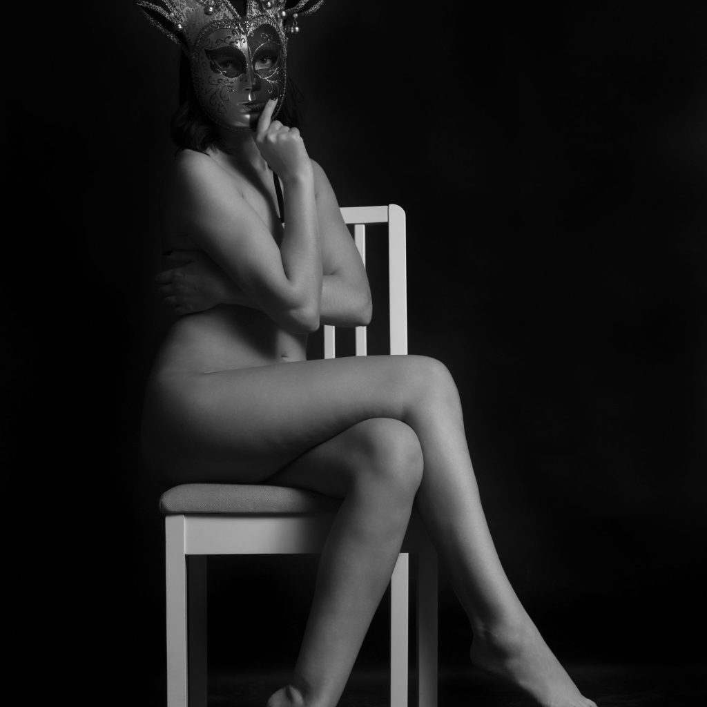 Fine art nude model pe scaun la studio purtand nimic altceva decat o masca