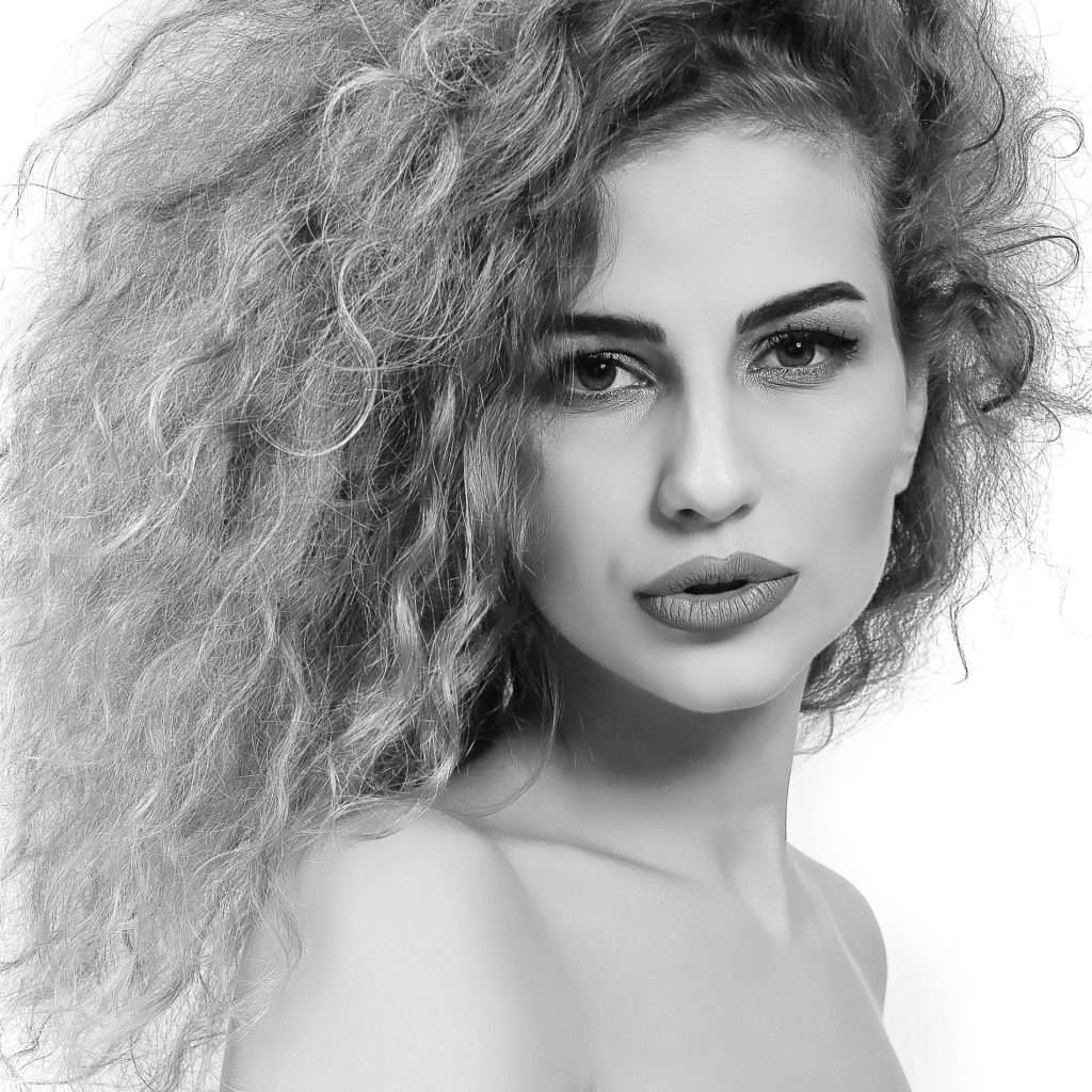 Portret artistic in studio, alb-negru. Model feminin cu par bogat exprimand gratie si liniste