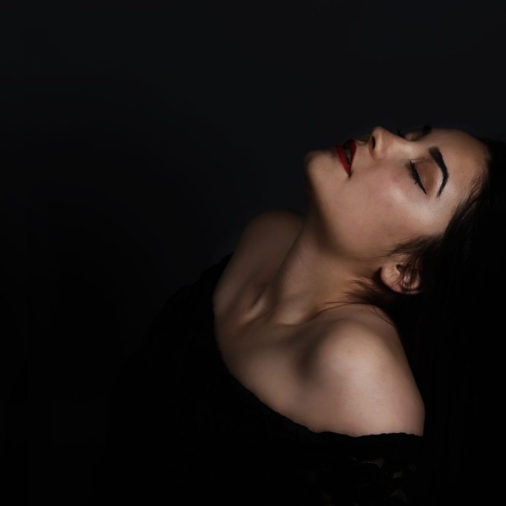 Detaliu de chip feminin surprins cu ochii inchisi, cu o pace interioara vizibila pe chip