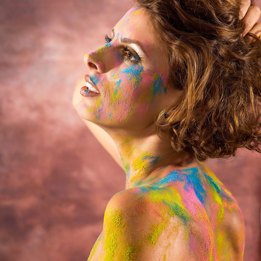 Portret feminin privind in stanga sus, acoperită de culori pe fata si corp