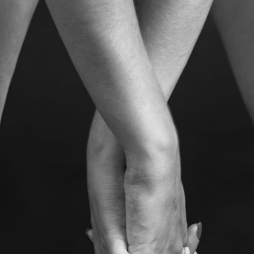 Fotografie boudoir care surprinde tandrețea și grația mâinilor modelului, cu brațele încrucișate, într-o lumină blândă de studio.