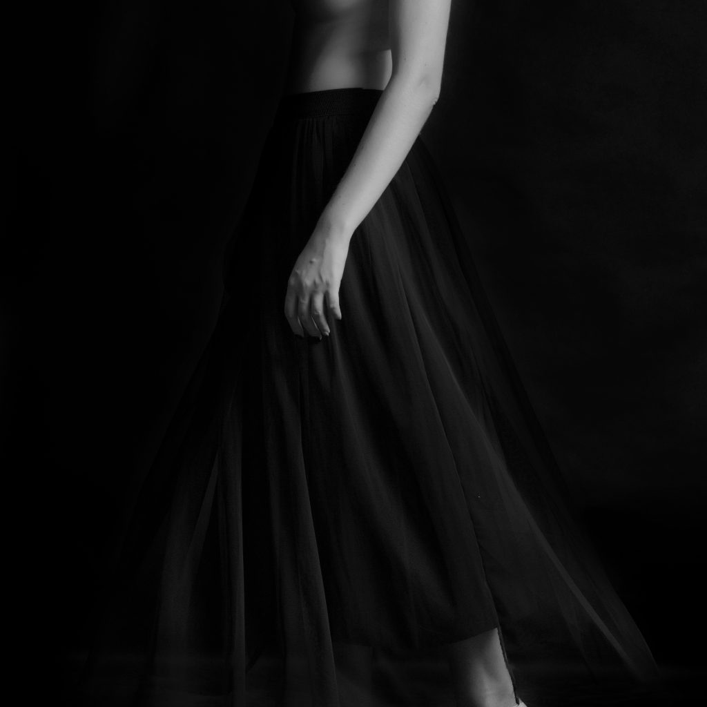 Portret boudoir alb-negru al unei femei, îmbrăcată într-un voal delicat, emanând mister și feminitate.